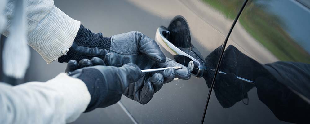 hands with a screw driver in a lock of a car in an attempt to steal the car
